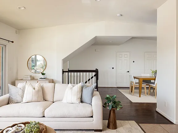 Living room couch with stairwell and dining beyond